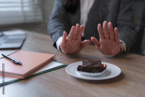 Obraz na płótnie Businesswoman refusing chocolate cake in office setting