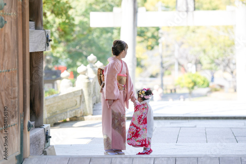 Photography A 3-year-old Japanese girl in a red kimono stands with her parents-mom in a pink kimono, dad in a suit-at a shrine for Shichi-Go-San