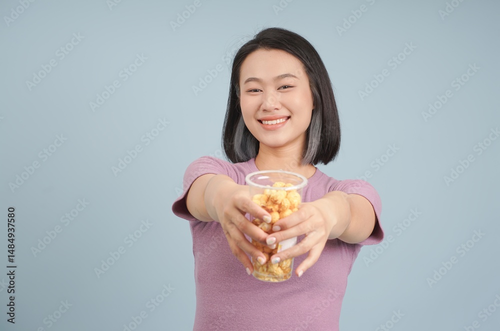 Young woman shares a cup of snack in a cheerful setting while wearing a casual outfit and smiling at the camera Young woman shares a cup of snack in a cheerful setting while wearing a casual outfit and smiling at the camera