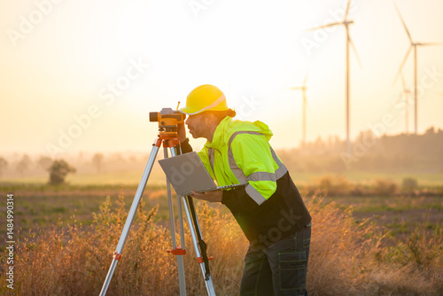 Engineer wearing uniform inspection and survey work in wind turbine farms rotation to generate electricity energy. Maintenance engineer working in wind turbine farm at sunset.