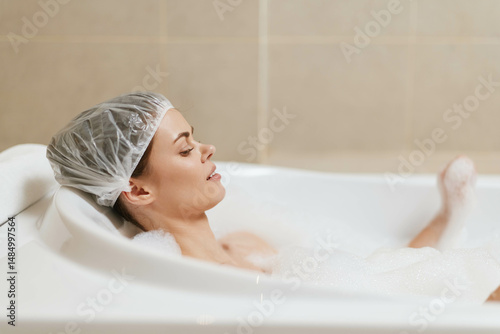 Relaxed woman enjoying a bubble bath at home, wearing a shower cap and soaking in a luxurious environment. Self-care and wellness concept.