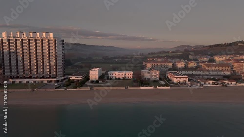 Aerial drone video of the Adriatic Sea at sunrise off Porto Potenza, Italy. Peaceful flyby capturing calm waters, golden reflections, and serene coastal beauty.