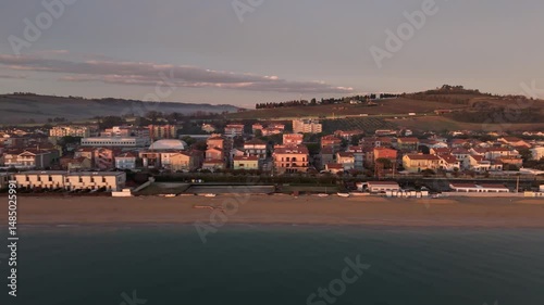 Aerial drone video of the Adriatic Sea at sunrise off Porto Potenza, Italy. Peaceful flyby capturing calm waters, golden reflections, and serene coastal beauty.