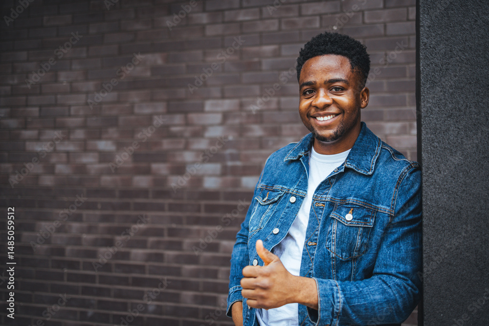 Obraz premium Smiling Man Giving Thumbs Up in Front of a Brick Wall Background