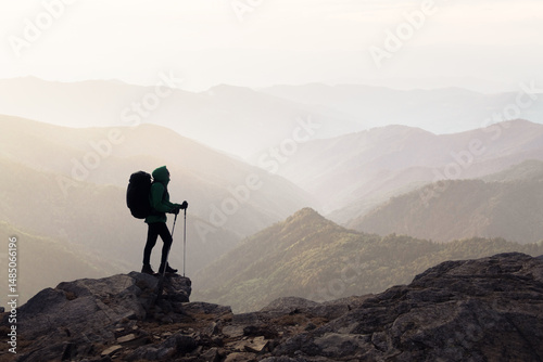 Silhouette of a hiker with a backpack against the background of misty mountains ranges. Travel and adventure concept