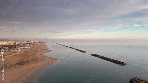 Aerial drone video of the Adriatic Sea at sunrise off Porto Potenza, Italy. Peaceful flyby capturing calm waters, golden reflections, and serene coastal beauty.