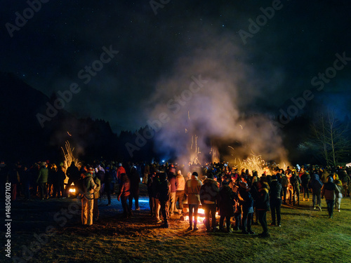 A large group of people stand around bonfires at night under a starry sky. Krampus and St Nicholas, 5 December in Tarvisio, Friuli Venezia Giulia, Julian Alps, Italy.