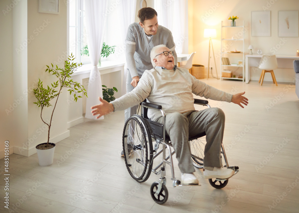 © Studio Romantic - Cheerful elderly man spreading arms while sitting in wheelchair pushed by smiling caregiver. Senior patient having fun and entertaining with male friendly nurse during rehabilitation in nursing home.