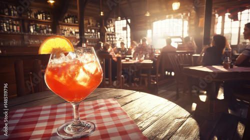 A vibrant cocktail with ice and an orange slice sits on a checkered tablecloth, capturing a warm, inviting ambiance.