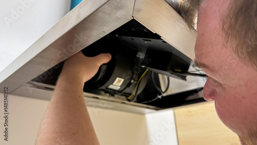 Caucasian male technician tweaking kitchen hood mechanics, capturing essence of Fix-it Friday, embracing the spirit of DIY Day
