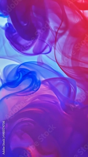 Abstract fluid paint mixing with vibrant red and blue colors spreading in water. Purple hues emerge as the paints blend and swirl together, creating mesmerizing patterns of flowing pigment.