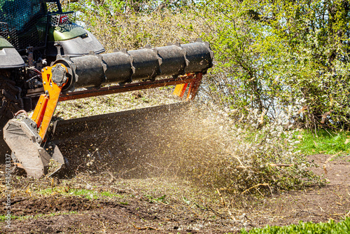 Picture of a tractor specialized in forest clearing that is in the process of destroying all the trees and bushes. Stop deforestation. Picture of a large tractor that destroys nature.