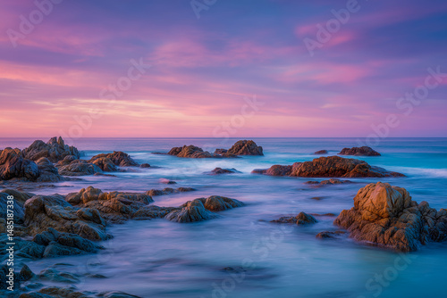  Long exposure of rocky coastline at sunset with soft pink and blue pastel tones in the sky and sea, evoking a peaceful and dreamlike atmosphere