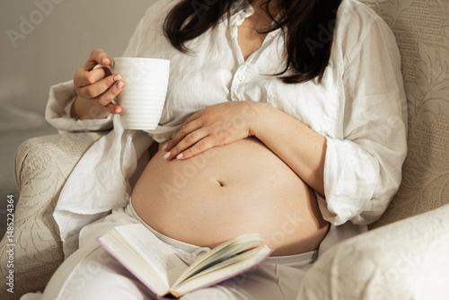 Pregnant woman relaxing with a book and cup of tea photo