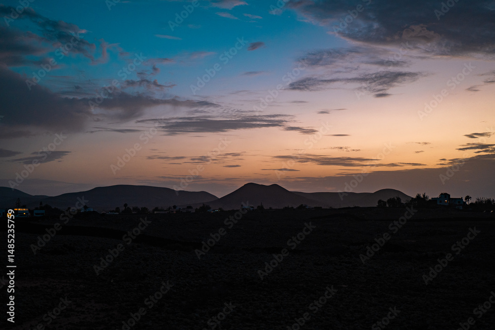 Naklejka premium Beautiful sunset over Fuerteventura mountains with vibrant colors and clouds