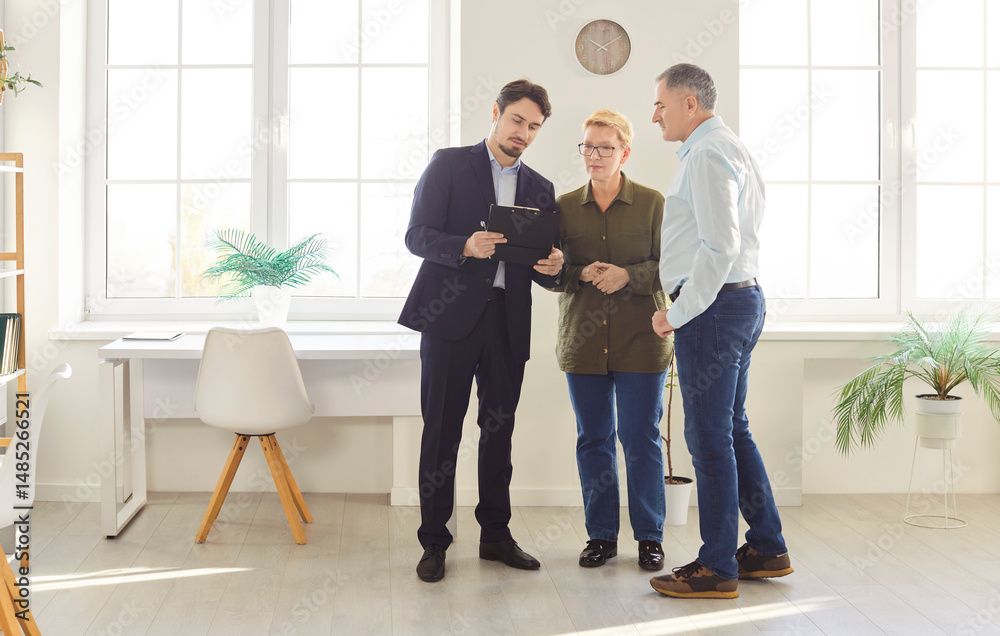 Fototapeta premium Attentive senior couple tours a new property with a real estate agent, discussing potential purchase or rental options. The visit highlights interest in real estate and future homeownership.