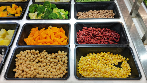 Colorful Salad Bar with Fresh Vegetables and Beans. A vibrant salad bar featuring fresh corn, chickpeas, red kidney beans, carrots, broccoli, and other vegetables. Ideal for promoting healthy eating,
