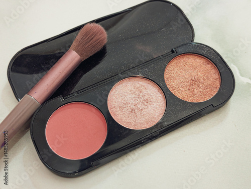 Close-up of an open makeup palette featuring three cosmetic powders blush, highlighter, and bronzer arranged in circular pans