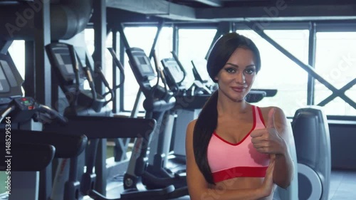 Confident girl in gym showing thumbs up with a radiant smile