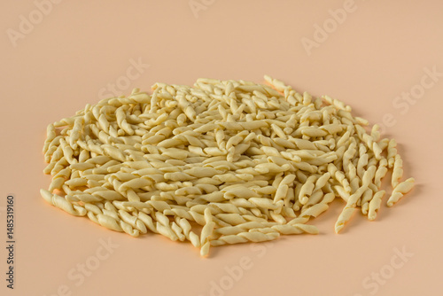 Pile of uncooked trofie pasta isolated on beige background, side view ,high-resolution . 