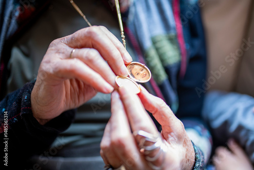 Fotografie Grandmother opens golden locket revealing grandchild's photo inside