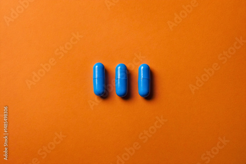 Blue capsules pills on orange background, closeup and space for text
