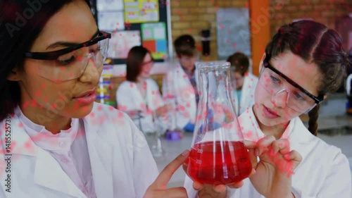 Students inspecting red liquid flask in chemistry lab, with red dashed lines highlighting data