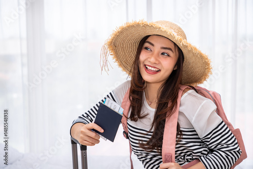 Smiling young Asian woman traveler with passport and boarding pass ready for vacation