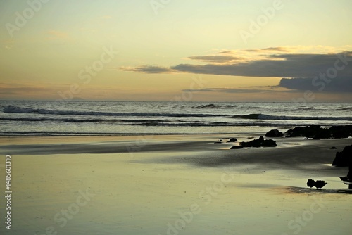 Silver light reflection over beach wet sand, yellowish light at horizon line, sunrise in Itacuruca beach, Cananeia, south Sao Paulo state 