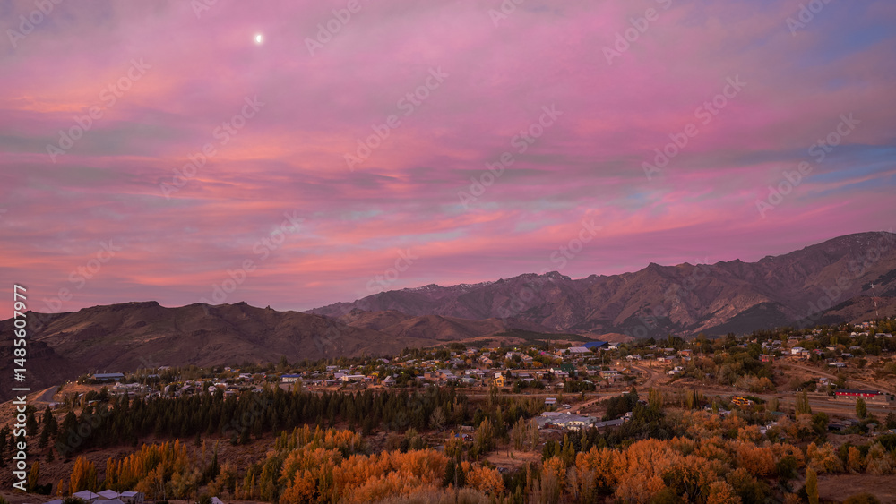Fototapeta premium Scenic view of Andacollo village at sunset nestled among autumn trees and mountains. Neuquen, Argentina