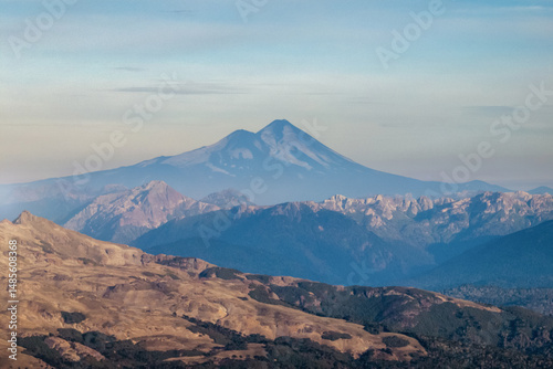 Majestic aerial view of Llaima snowcapped volcano under a soft, hazy sky in Patagonia