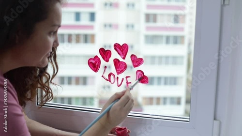 Woman with brush in hand painting pink hearts and the word 