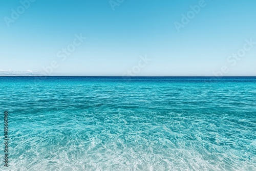 Calm turquoise ocean reflecting pristine blue sky on sunny day