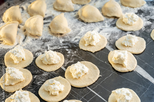 Raw varenyky on a black countertop, top view. The process of making Ukrainian varenyky with cottage cheese.