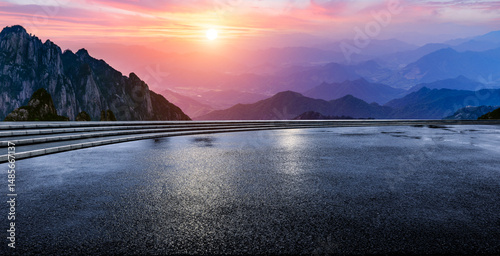 Fototapeta Naklejka Na Ścianę i Meble -  Wet asphalt road and mountain range with beautiful sky clouds at sunset