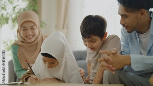 Islamic learning concept of 4k resolution. An Asian Muslim family is having fun writing words in a notebook together.