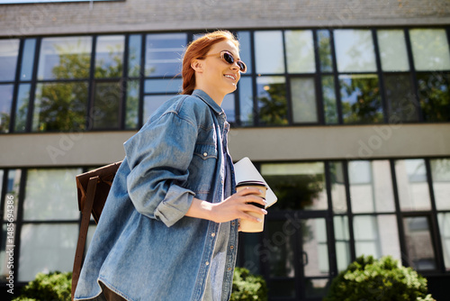 Εκτύπωση καμβά Red haired woman enjoying a sunny day while walking with coffee in a lively urba