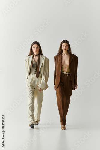 Stylish twin sisters confidently strut down a minimalist runway showcasing modern fashion