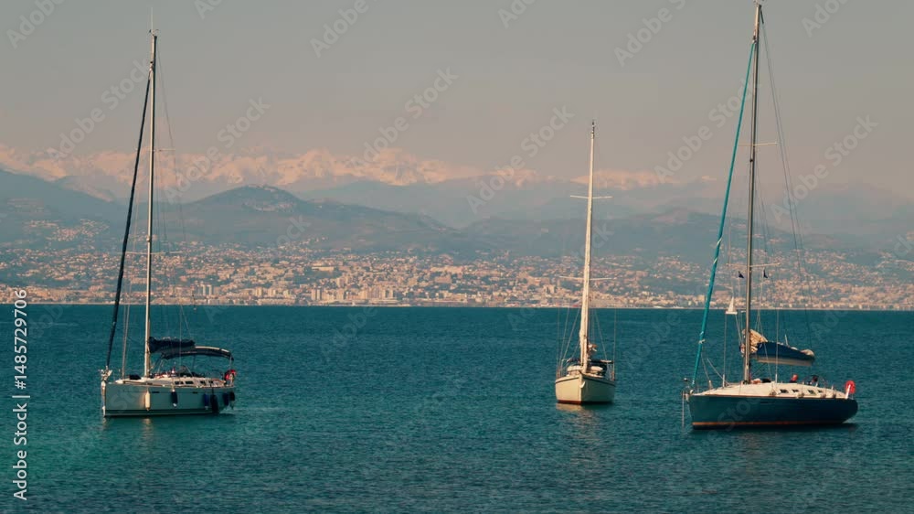Boats floating on the sea with the buildings and mountains of the French Riviera in the background Boats floating on the sea with the buildings and mountains of the French Riviera in the background