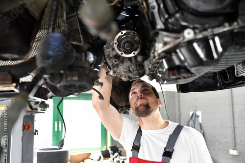 car mechanic in work clothes checks engine from a car in a workshop