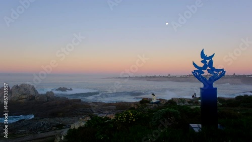 View of full moonset at blue hour from Hermanus coastline with artwork