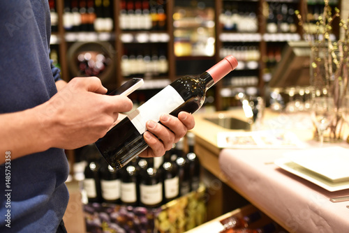 young couple in the supermarket shopping and choosing a bottle of wine