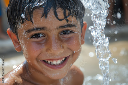 Young boy smiling and playing in a fountain. photo