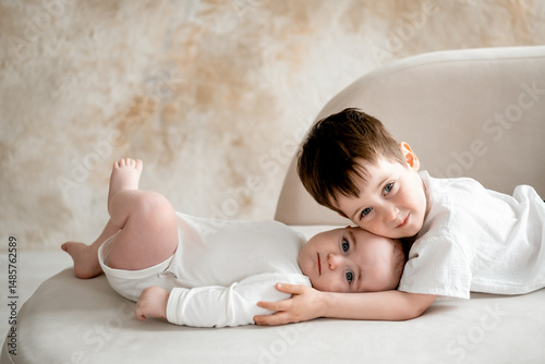 two brothers, two small children hug and kiss, a child kisses the baby's feet, brotherly love