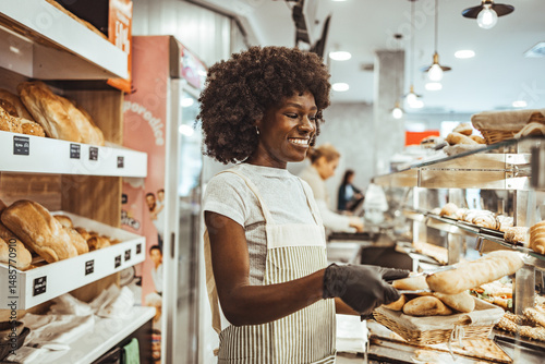 Smiling Baker Displaying Fresh Bread in a Modern Bakery Environment