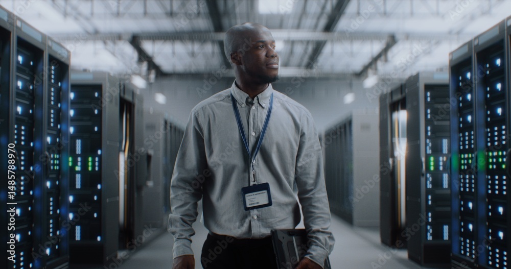Fototapeta premium Big Data Center with Server Racks: Professional African American Specialist with Tablet Computer Walking In Warehouse. Internet Servers, Information Technology, Cyber Security and Telecommunications.