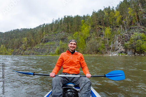 An adventurous kayaker fully enjoys the profound serenity found on a tranquil river, which is surrounded by an abundance of lush green forests that enhance the beauty of the natural landscape