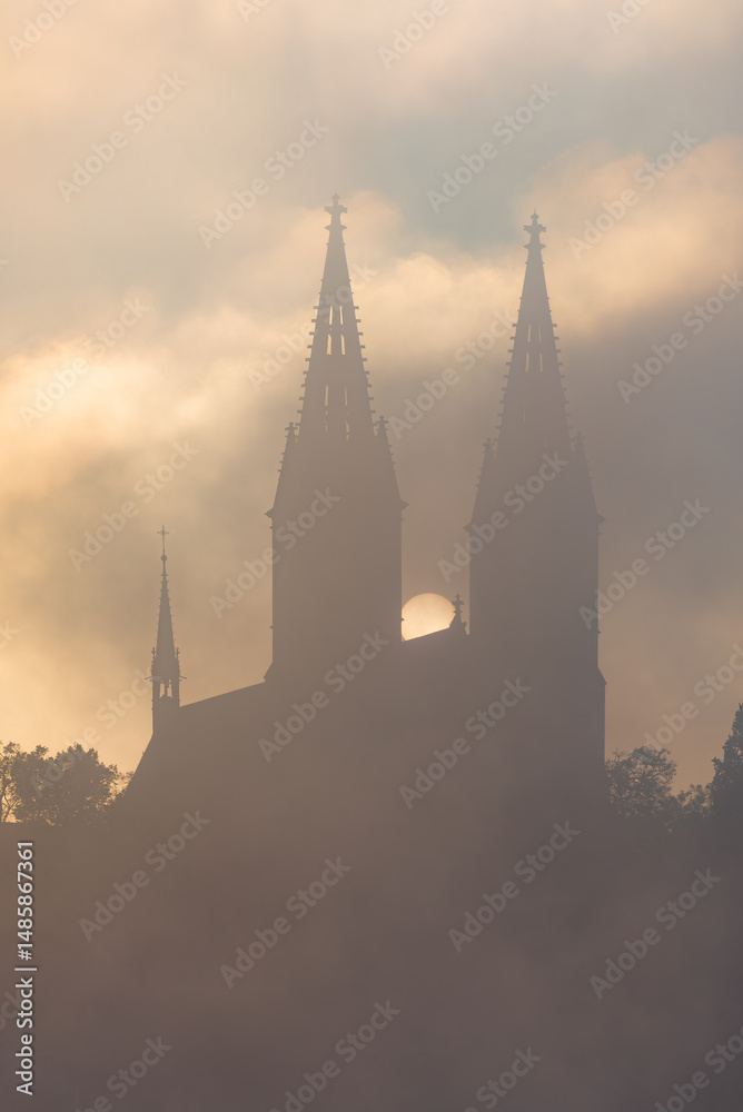 Obraz premium The Vysehrad basilica in the early morning fog and clouds in Autumn in UNESCO city site Prague.
