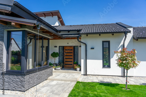 A contemporary house entrance showcasing sleek architecture, greenery, and a welcoming pathway, emphasizing modern design elements and harmonious outdoor integration