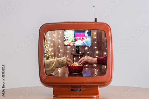 Tv showing movie of Christmas eve. Alone woman eating popcorn, watching tv, switching channels using remote control. Home cinema. Cropped, close up